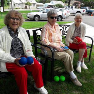 Three seniors enjoying a playful moment outdoors, ready for some fun with colored balls.