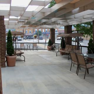 A covered outdoor patio with seating and potted plants.