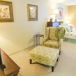 Cozy living room with an armchair and ottoman set, adorned with decorative art and a lamp.