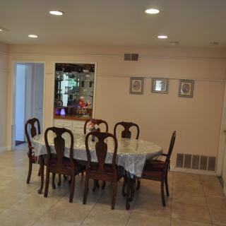A well-lit dining area featuring a large table and chairs with a decorative mirror on the wall.