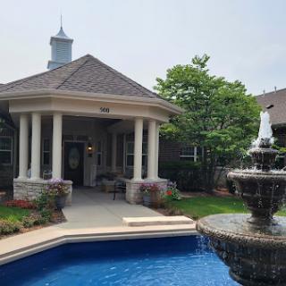 A beautiful house featuring a serene pool and fountain surrounded by lush greenery.
