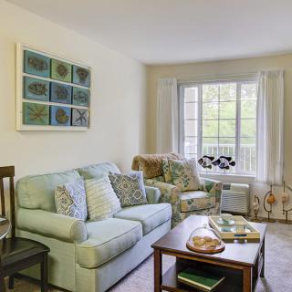 A cozy living room with a sofa, armchair, and a coffee table near a large window.