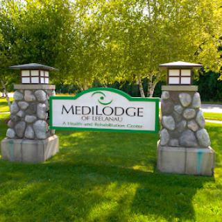 Entrance sign for MediLodge, a healthcare facility surrounded by greenery.