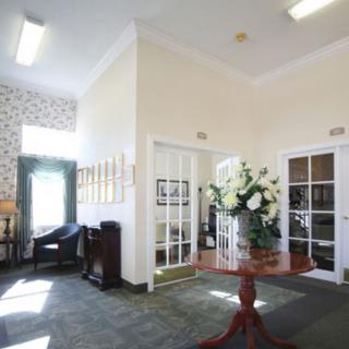 A well-lit lobby area with a floral arrangement on a wooden table and comfortable seating.