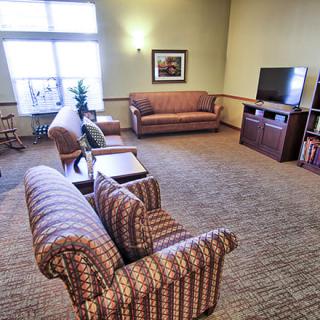 A cozy living room with sofas, a television, and large windows letting in natural light.