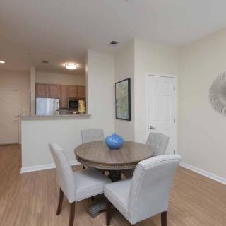 Modern dining area with a round table and upholstered chairs adjacent to an open kitchen.