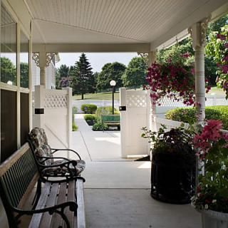 A cozy porch with benches and blooming flowers overlooks a well-maintained garden.