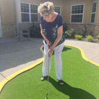 A woman practicing her putting on a mini golf course outdoors.