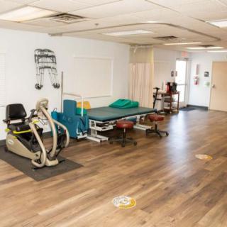 An indoor physical therapy treatment room equipped with exercise machines and therapy beds.