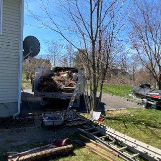 A yard in the midst of a home renovation, featuring a dumpster full of debris and tools scattered around.