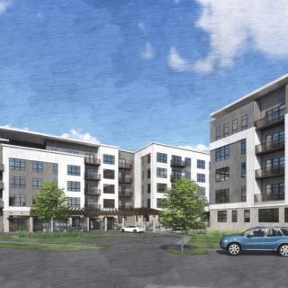 A modern apartment complex with multiple stories, featuring a parking lot and a car in the foreground under a clear blue sky.