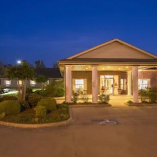 A well-lit building entrance at night with decorative landscaping.