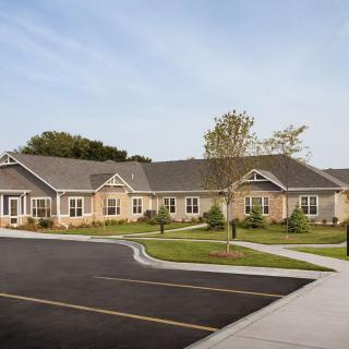 A single-story residential building with a neatly maintained lawn and adjacent parking lot.