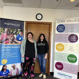 Two individuals standing in front of informative banners highlighting healthcare values and community support.