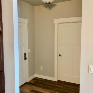 A hallway with two doors, featuring a light fixture and wood flooring.