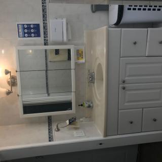 A clean and organized bathroom with a mirror, sink, and cabinet.