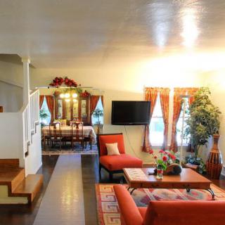 A cozy living room with orange seating, a television, and a view into the dining area.