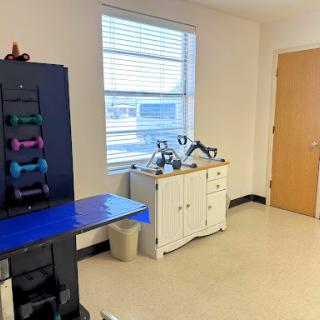 A well-lit room featuring a variety of exercise weights and a white cabinet.