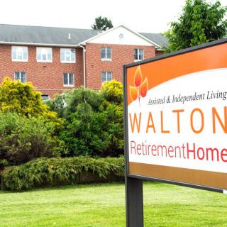 A retirement home with a sign in front, surrounded by well-maintained landscaping.