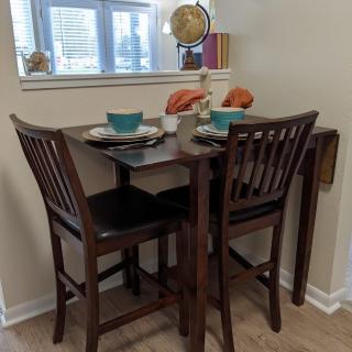 A cozy dining nook with a small set table and two chairs, accented by a globe and natural light from the window.