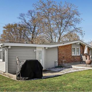 Suburban backyard with a brick house, patio, and grill.