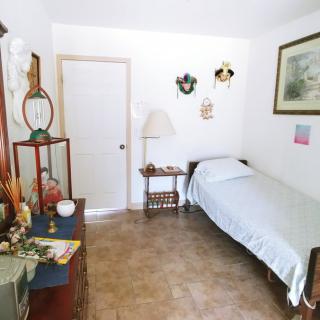 A cozy bedroom with a single bed, decorated walls, and a shelving unit.