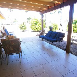 A cozy outdoor patio with a swing and seating area under a covered structure.