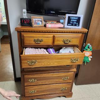 A wooden dresser with several drawers, partially opened to reveal neatly folded clothes.