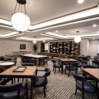 A modern dining area with neatly arranged tables and chairs, illuminated by elegant ceiling lights.