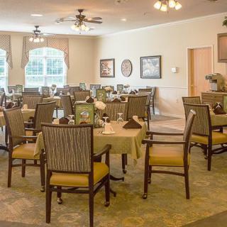 A well-set dining room with multiple tables and chairs, featuring elegant decor and ambient lighting.