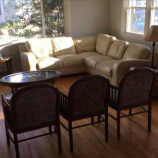 A sunlit living room with a beige sofa, several chairs, and a coffee table.