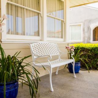 A quaint porch with a white bench and potted plants.