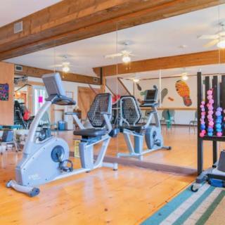 A well-equipped gym featuring exercise bikes, mirrors, and a rack of dumbbells.