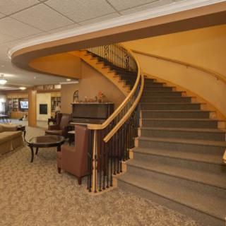 A warmly lit interior with a curved staircase and seating area.