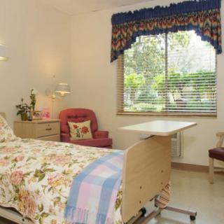 A cozy hospital room with a bed, window, and comfortable seating.