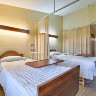 A hospital room with two beds separated by privacy curtains.