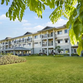 A residential apartment building surrounded by lush greenery and a well-maintained lawn.