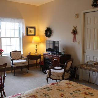 A cozy living room with classic furniture, a television, and soft lighting from a lamp by the window.