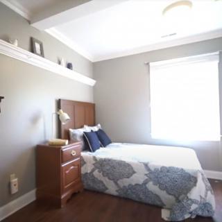 A cozy bedroom with a bed, dresser, and window letting in natural light.
