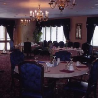 A dimly lit dining room with elegant chandeliers and set tables.