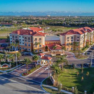 Aerial view of a luxurious hotel resort surrounded by palm trees and green landscapes.