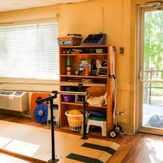 A bright and inviting indoor space equipped for rehabilitation exercises, featuring organized storage and natural light.