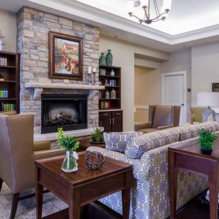 A cozy living room with a stone fireplace, elegant furniture, and tasteful decor.