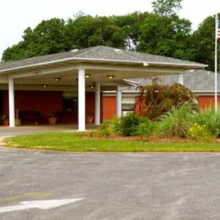 A building entrance with a covered driveway and landscaped surroundings.