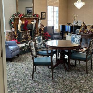 A cozy living room decorated for Christmas, featuring a round table with chairs and a fireplace adorned with stockings.