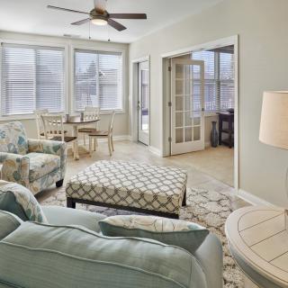 A cozy living room with pastel-colored furniture and an adjoining dining area.