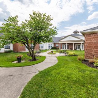 A landscaped courtyard with a winding pathway and brick buildings under a cloudy sky.