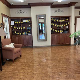 A warm and inviting lobby with wooden flooring, stylish furniture, and decorative shelves.