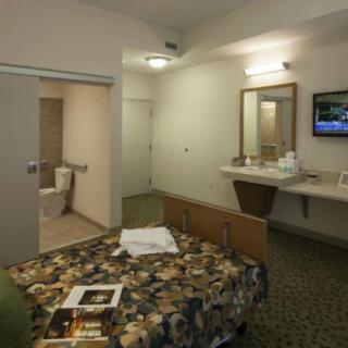 A basic hotel room with a bed, attached bathroom, sink area, and television.
