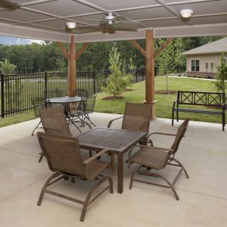 A covered patio with outdoor furniture set, overlooking a garden.
